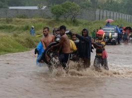 Banjir, Warga Alor Pikul Kenderaan Seberang Jalan Nasional Pemuda Desa Lembur sedang memikul kenderaan roda dua akibat banjir di jalan Nasional Kalabahi - Maritaing, Jumat (2/4/2021) siang.