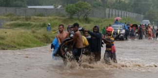Banjir, Warga Alor Pikul Kenderaan Seberang Jalan Nasional Pemuda Desa Lembur sedang memikul kenderaan roda dua akibat banjir di jalan Nasional Kalabahi - Maritaing, Jumat (2/4/2021) siang.