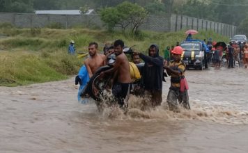 Banjir, Warga Alor Pikul Kenderaan Seberang Jalan Nasional Pemuda Desa Lembur sedang memikul kenderaan roda dua akibat banjir di jalan Nasional Kalabahi - Maritaing, Jumat (2/4/2021) siang.